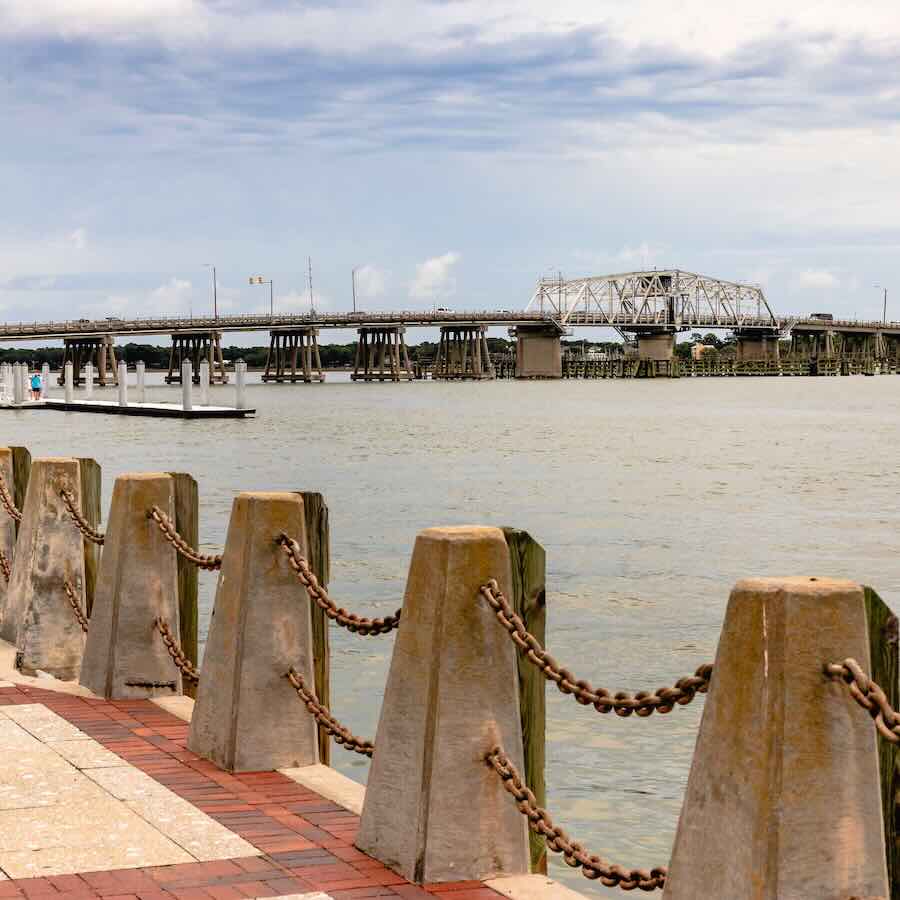 Bridge over river with wooden barriers along shoreline.