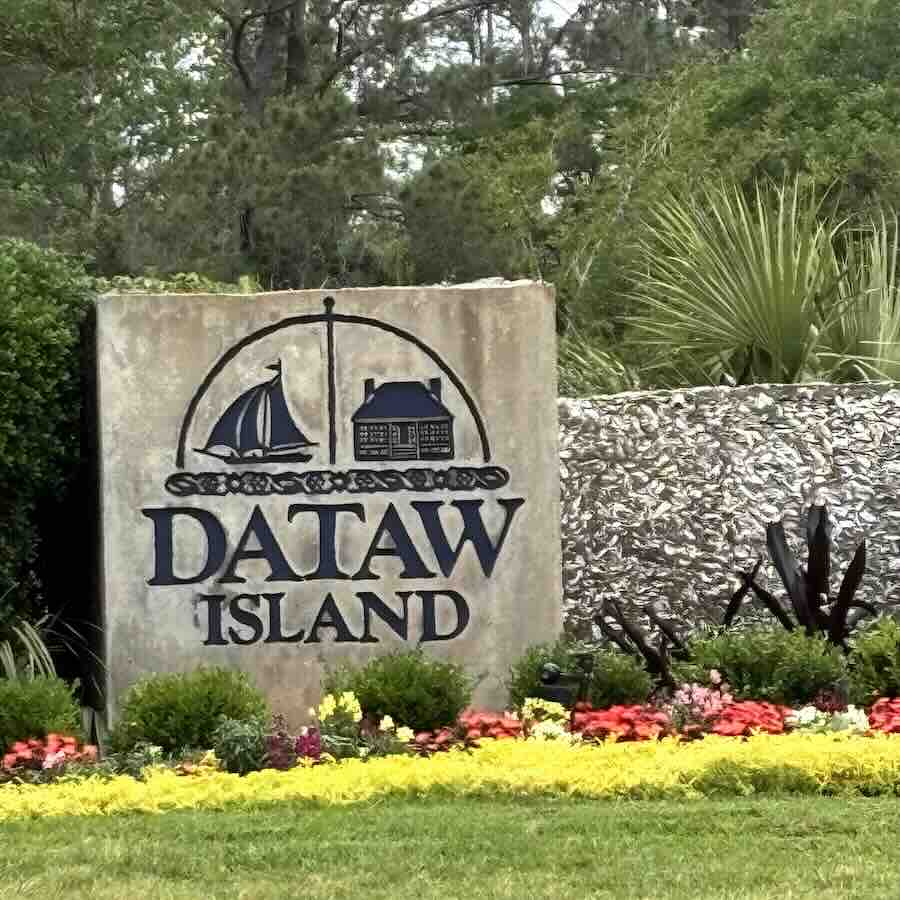 Dataw Island entrance sign with greenery and flowers.