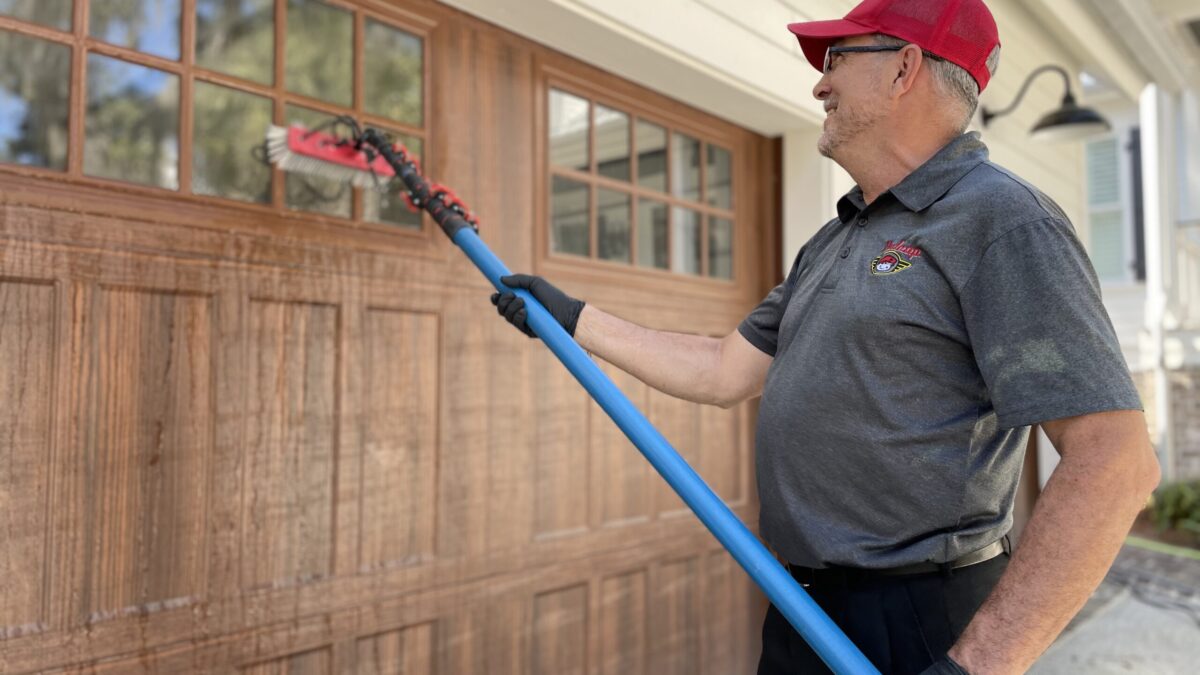 Man cleaning garage windows with brush tool.