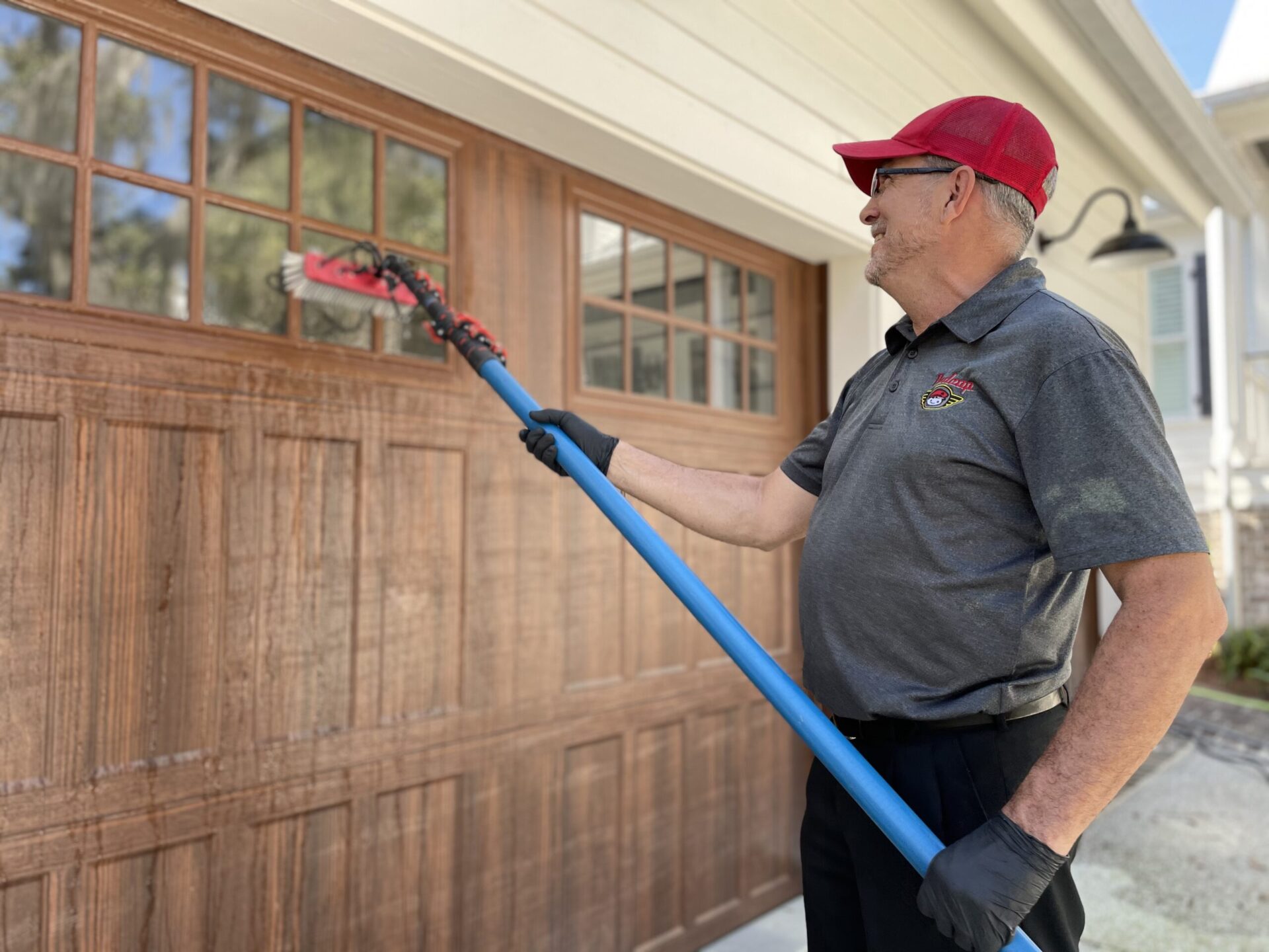 Man cleaning garage windows with brush tool.