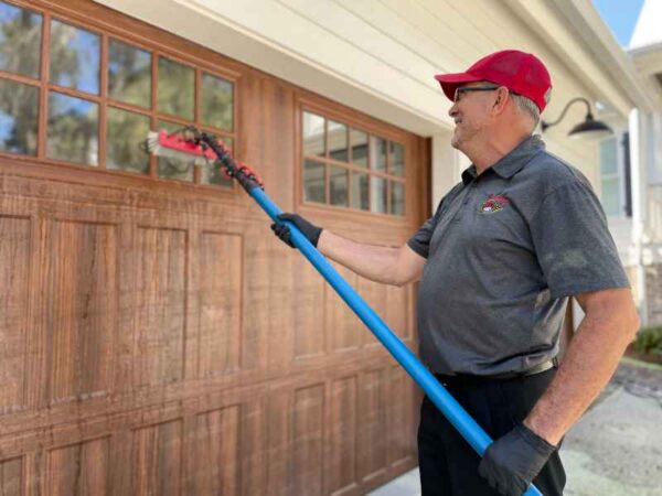 Man cleaning garage windows with brush tool.