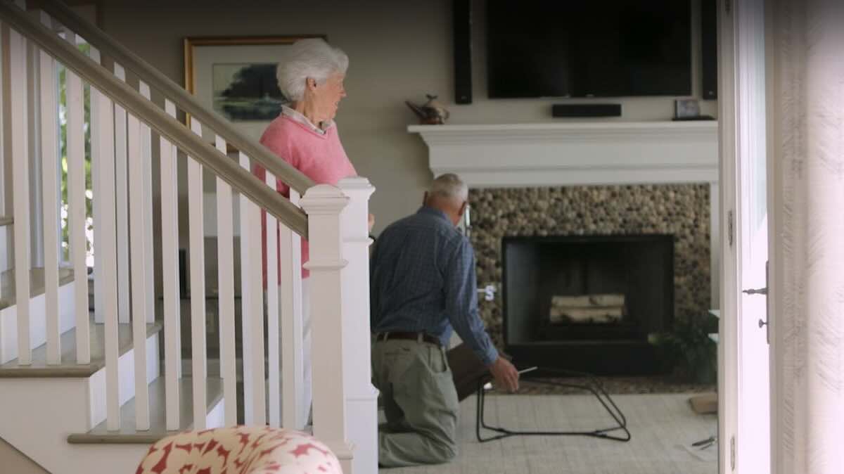 Elderly man assembling small table in living room.