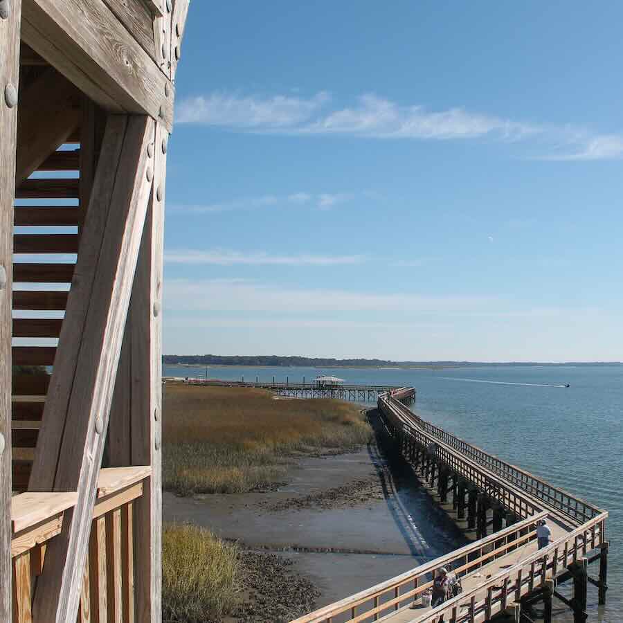 Wooden pier extending over the water, marsh landscape.