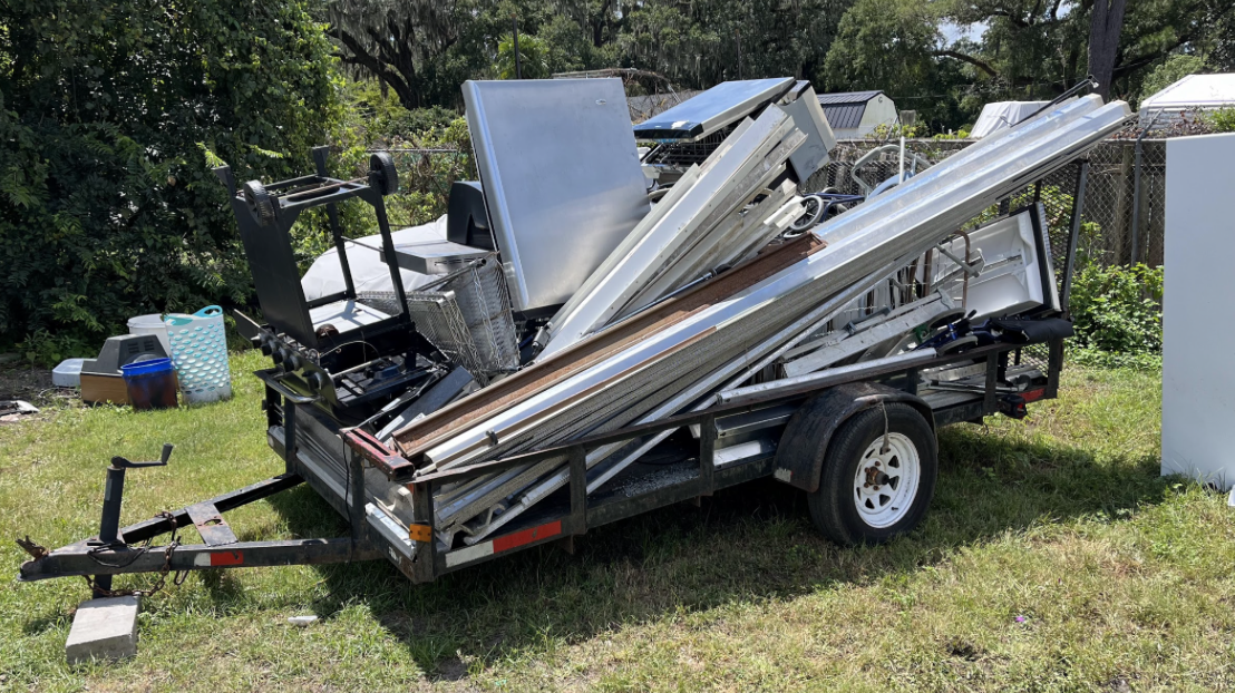 Trailer overloaded with metal items and scrap.