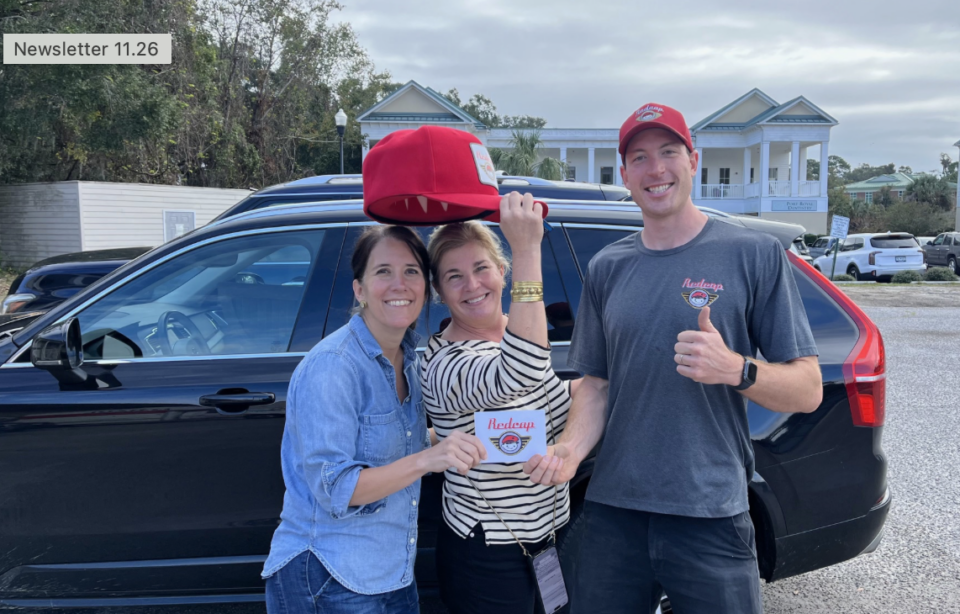 Smiling group holding Redcap delivery card and cap.