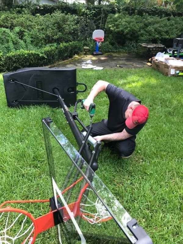 Man assembling backyard basketball hoop