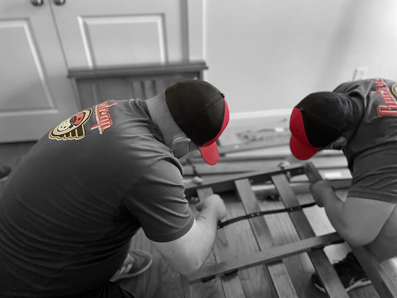Two people fixing a wooden furniture piece.