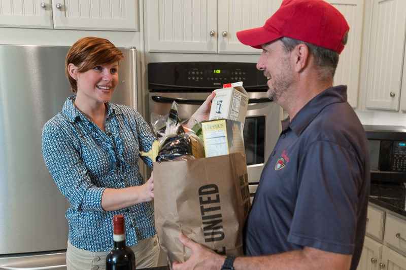 Man delivering groceries to a smiling woman.