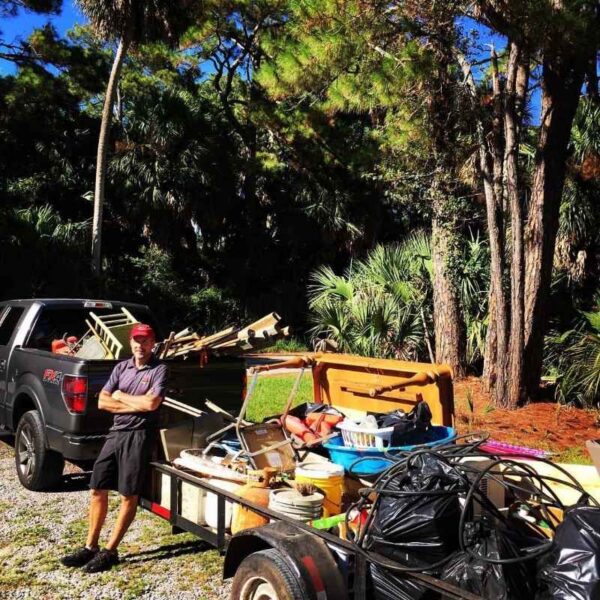 Man with truck and trailer full of items outdoors.