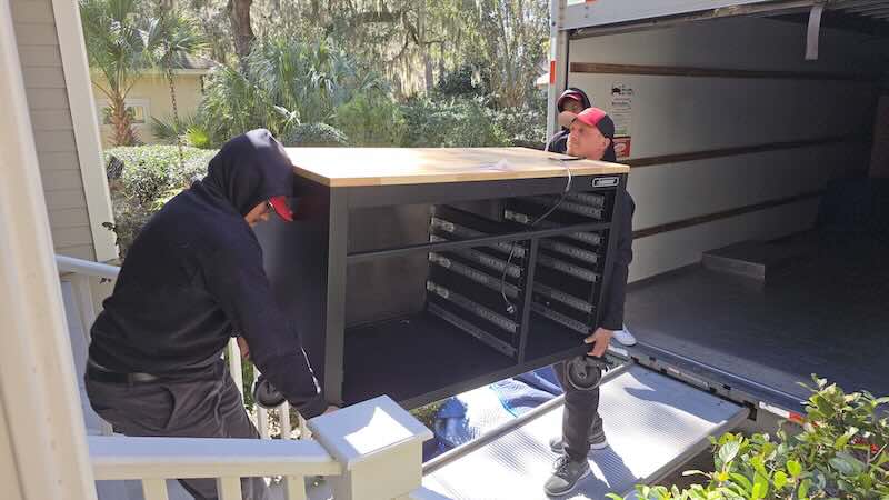 Movers carrying a large cabinet to truck