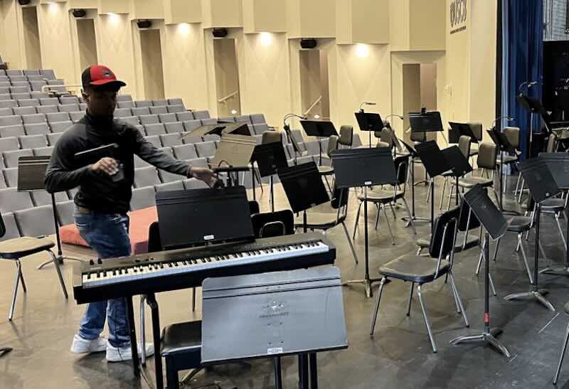 Man setting up music stands in an auditorium.