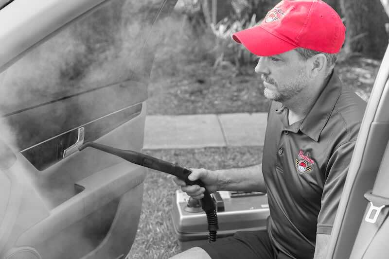 Man steam cleaning car interior door.